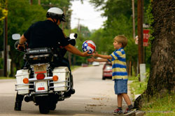 Police officer handing ball to child