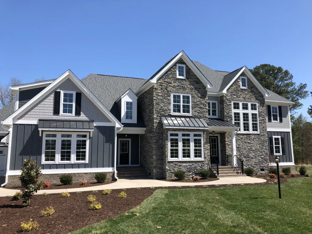 Gray two-story custom home with a stone front and a landscaped lawn